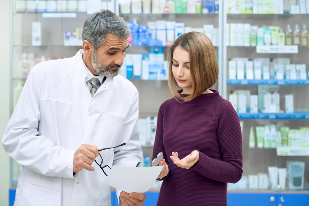 Apotheker erklärt einer Kundin ein Rezept